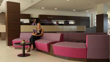 A reception area with a reception desk, a pink sofa, and a small table with a decorative item.
