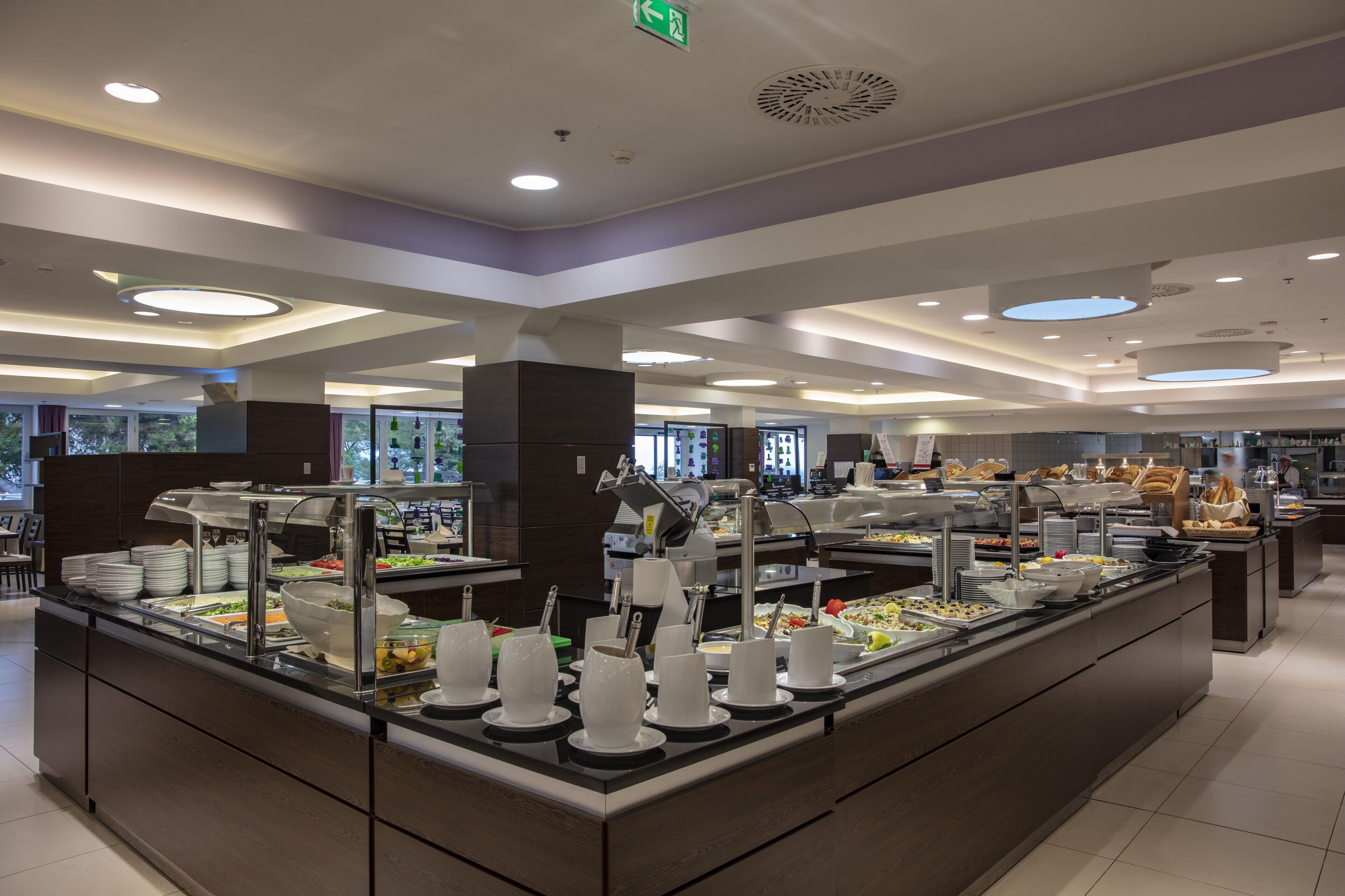 A buffet area with various food stations and a glass partition.