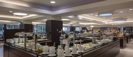 A buffet area with various food stations and a glass partition.