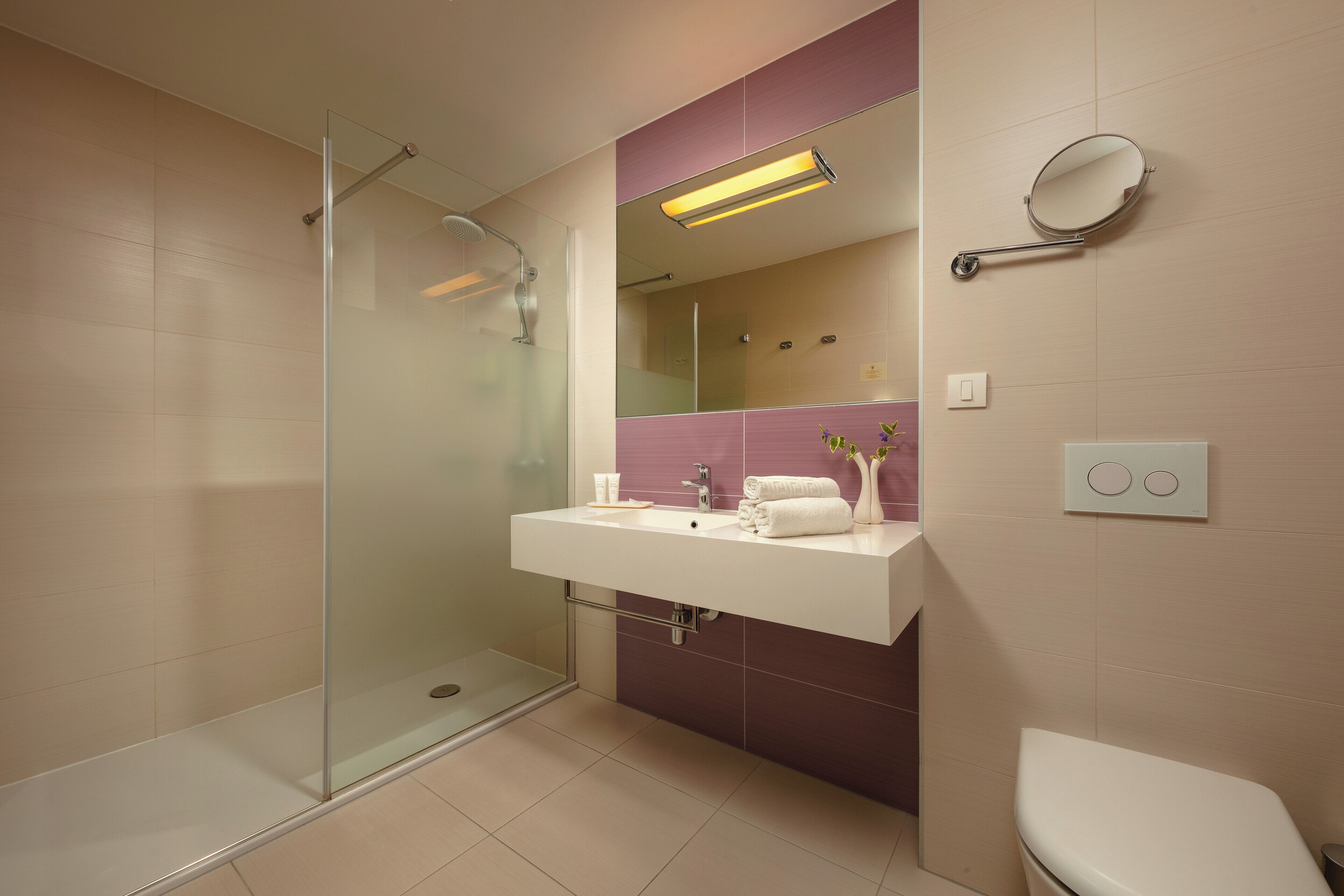 A modern bathroom with a glass-enclosed shower, a white sink with a mirror, and a white toilet.