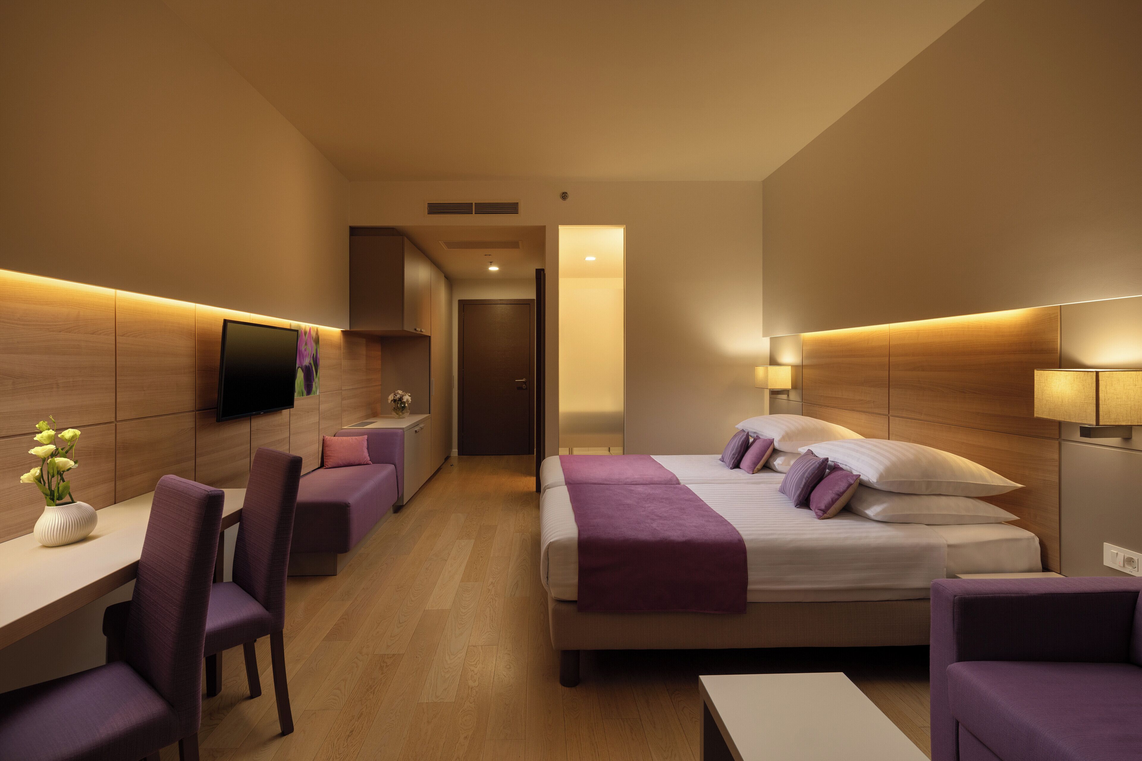 Une chambre d’hôtel moderne, équipée d’un lit, d’un bureau et de chaises.