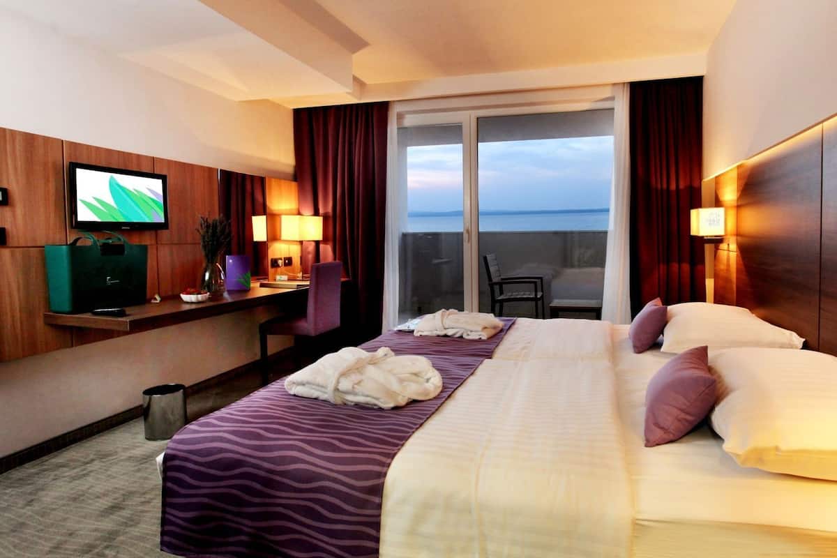 Habitación de hotel con cama, escritorio, televisión y vista al mar.