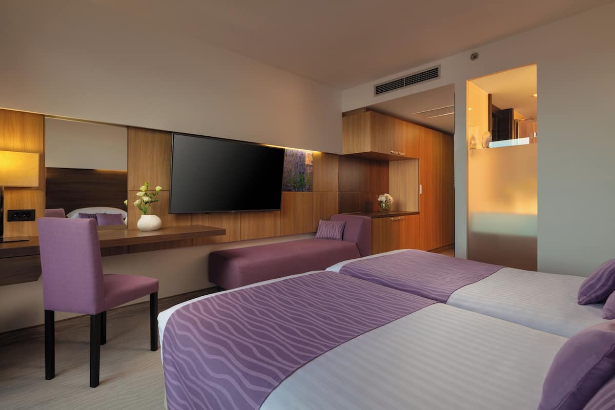 Una habitación de hotel moderna con una cama grande, un área de descanso, un televisor de pantalla plana y una pared de acento de madera.