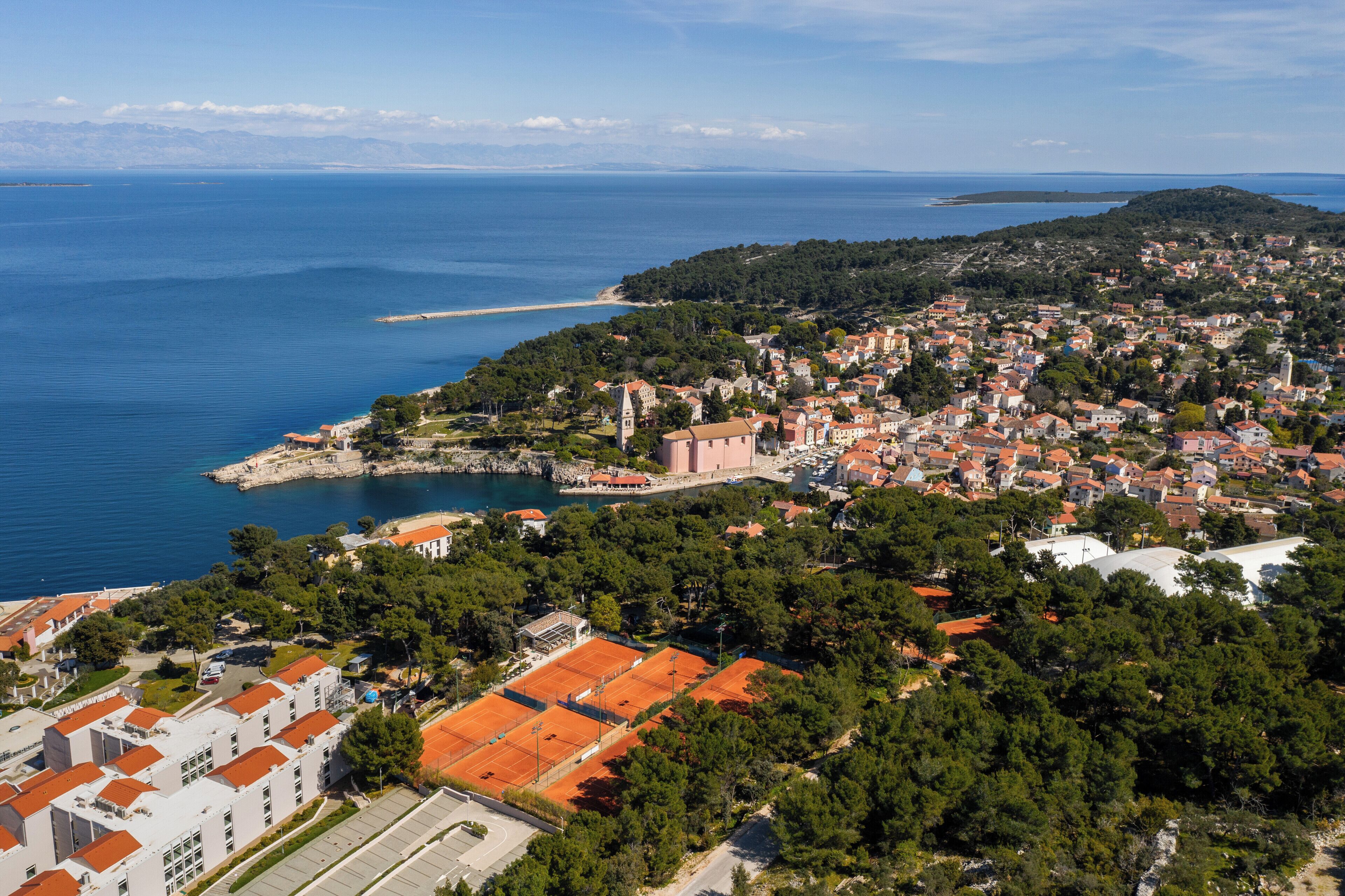 An aerial view of a coastal town with a mix of residential and commercial buildings, a prominent church, and a beach.