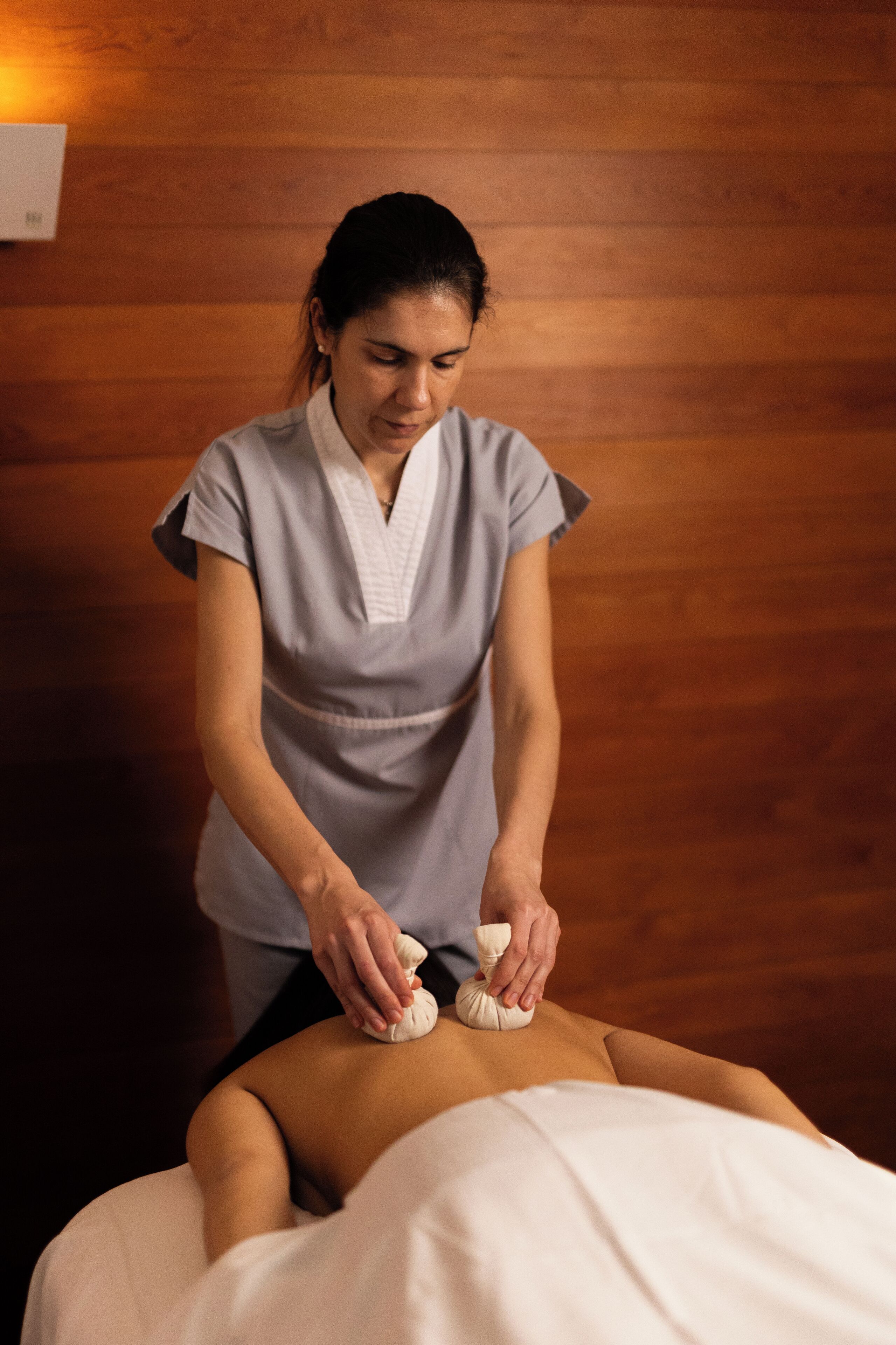 A person receiving a massage in a room with wooden paneling.