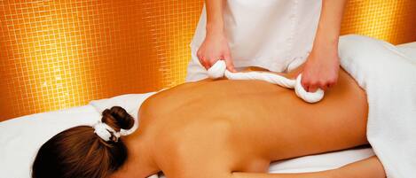 A person receiving a massage in a room with a tiled wall.