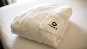 Una toalla blanca doblada con un logotipo, colocada sobre una cama.