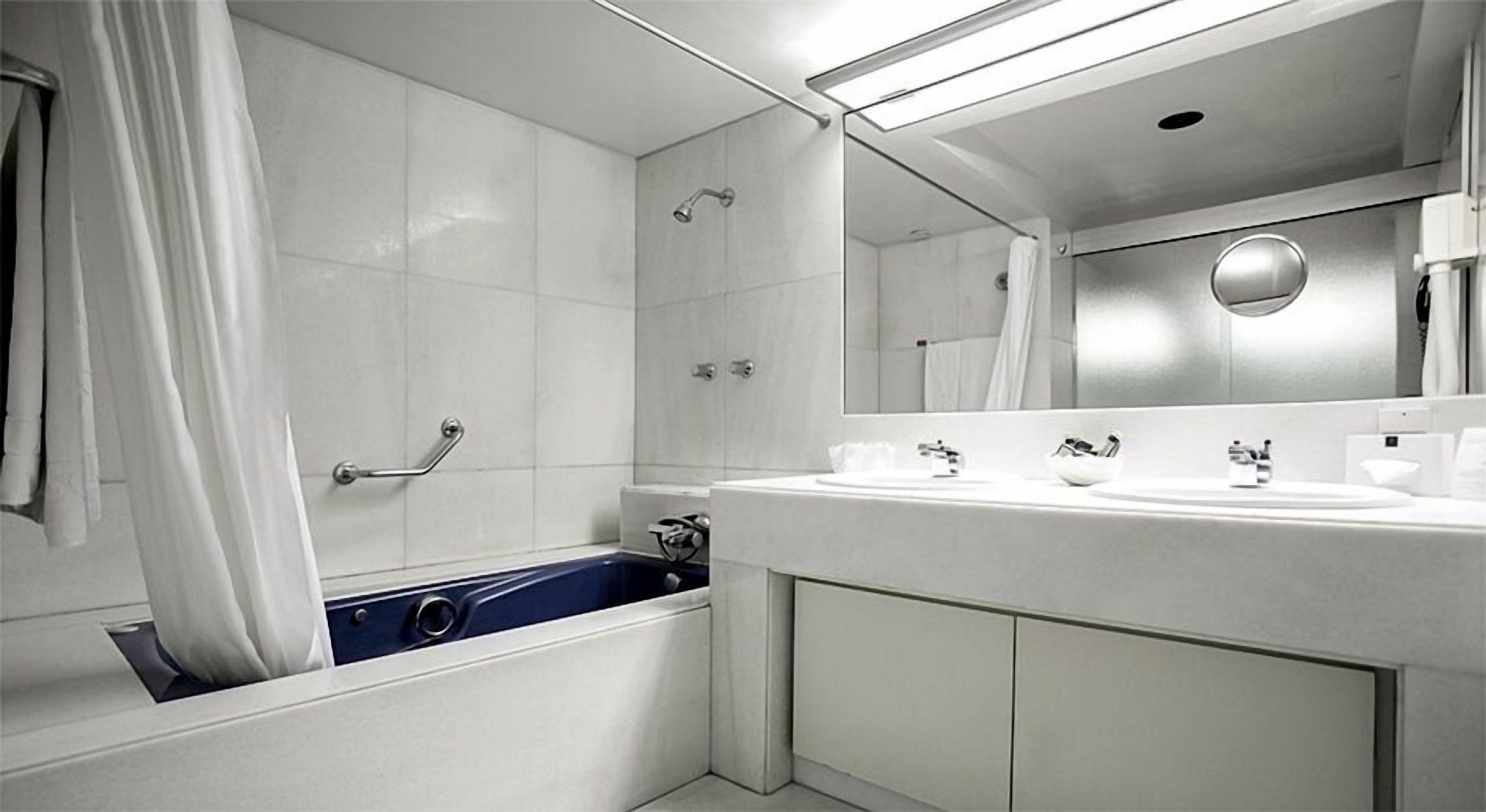 Une salle de bain moderne équipée d’une baignoire, d’une douche et d’un meuble-lavabo avec deux vasques.