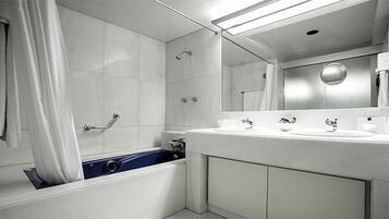 Une salle de bain moderne équipée d’une baignoire, d’une douche et d’un meuble-lavabo avec deux vasques.