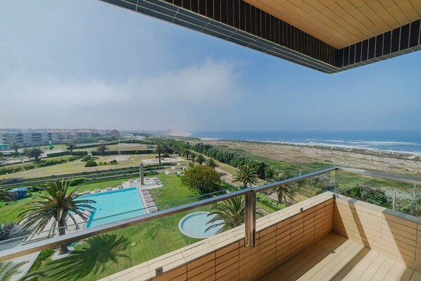 Un balcon avec vue sur une piscine et l’océan.