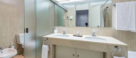 A modern bathroom with two sinks, a large mirror, a towel rack, and a shower area.