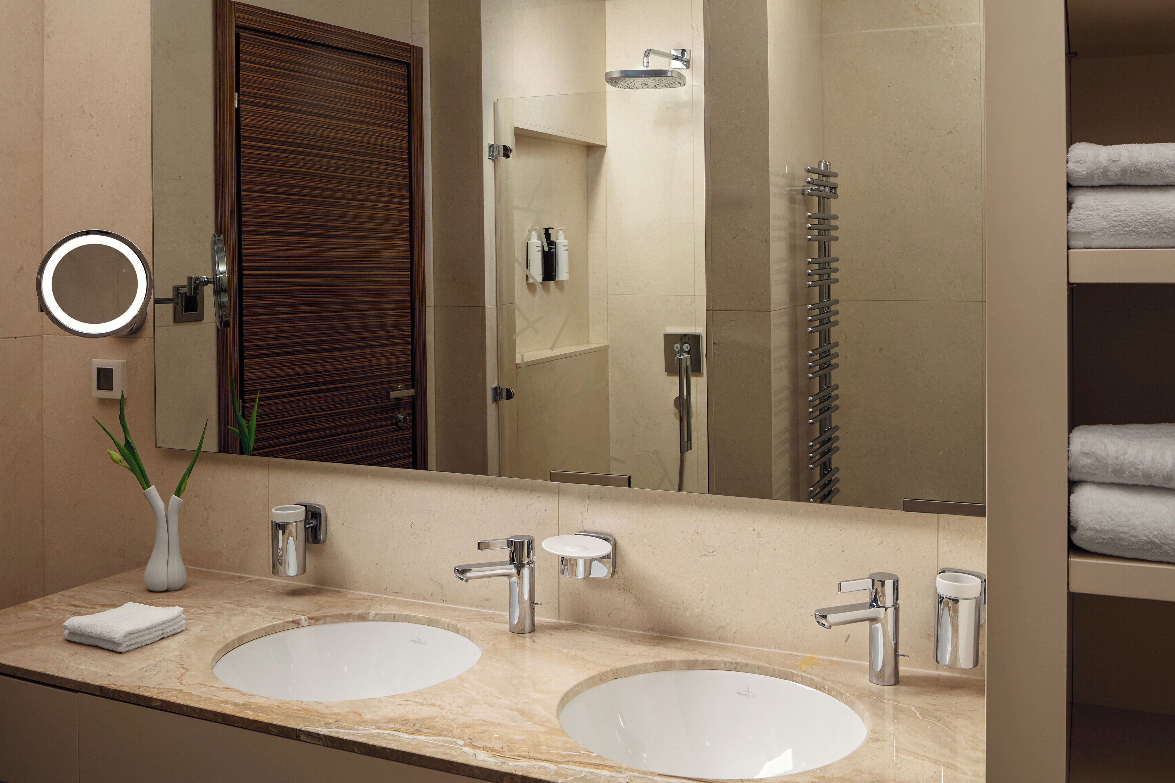 A modern bathroom with two sinks, a shower, and a vanity with a mirror.