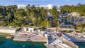 Un hotel frente al agua con zonas de estar al aire libre, piscina y vistas de los edificios y árboles circundantes.