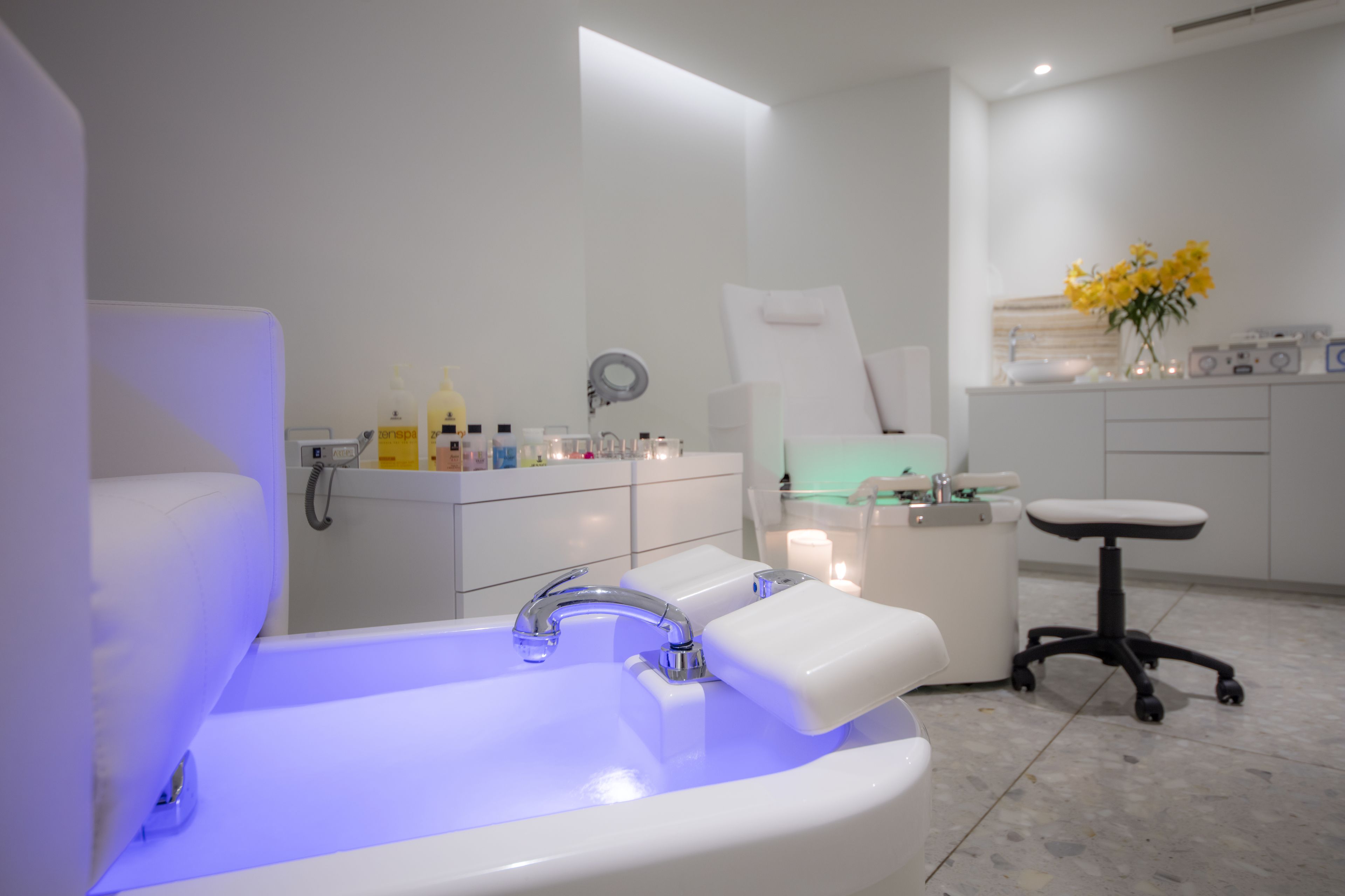 A modern bathroom with a white sink, a large mirror, and a white chair.