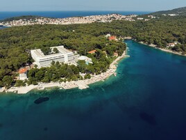 Vista aérea de una zona costera con un edificio grande, una playa y aguas azul turquesa.