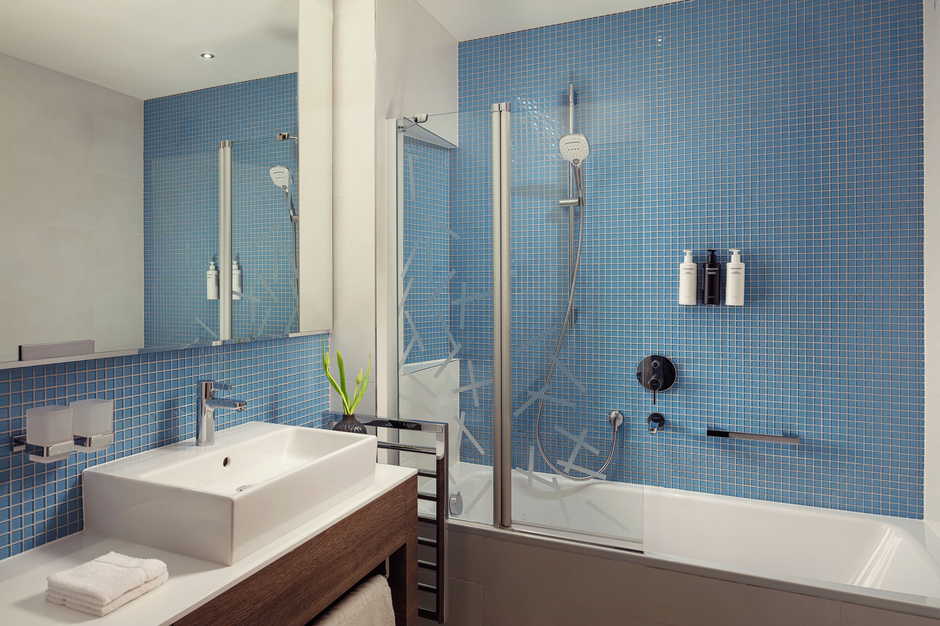 Un baño moderno con un lavamanos grande de color blanco, una cabina de ducha de vidrio y una bañera.
