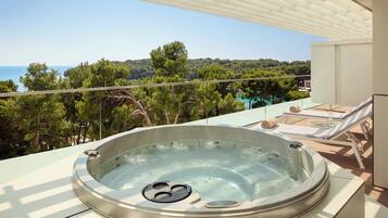 Un jacuzzi en un balcón con vistas al mar y a los árboles.