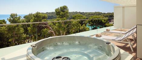 Un jacuzzi en un balcón con vistas al mar y a los árboles.