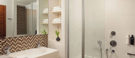 A modern bathroom with a glass-enclosed shower, a large mirror, and a checkered tile backsplash.