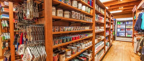 A store with wooden shelves stocked with various items like mugs, jars, and bags.