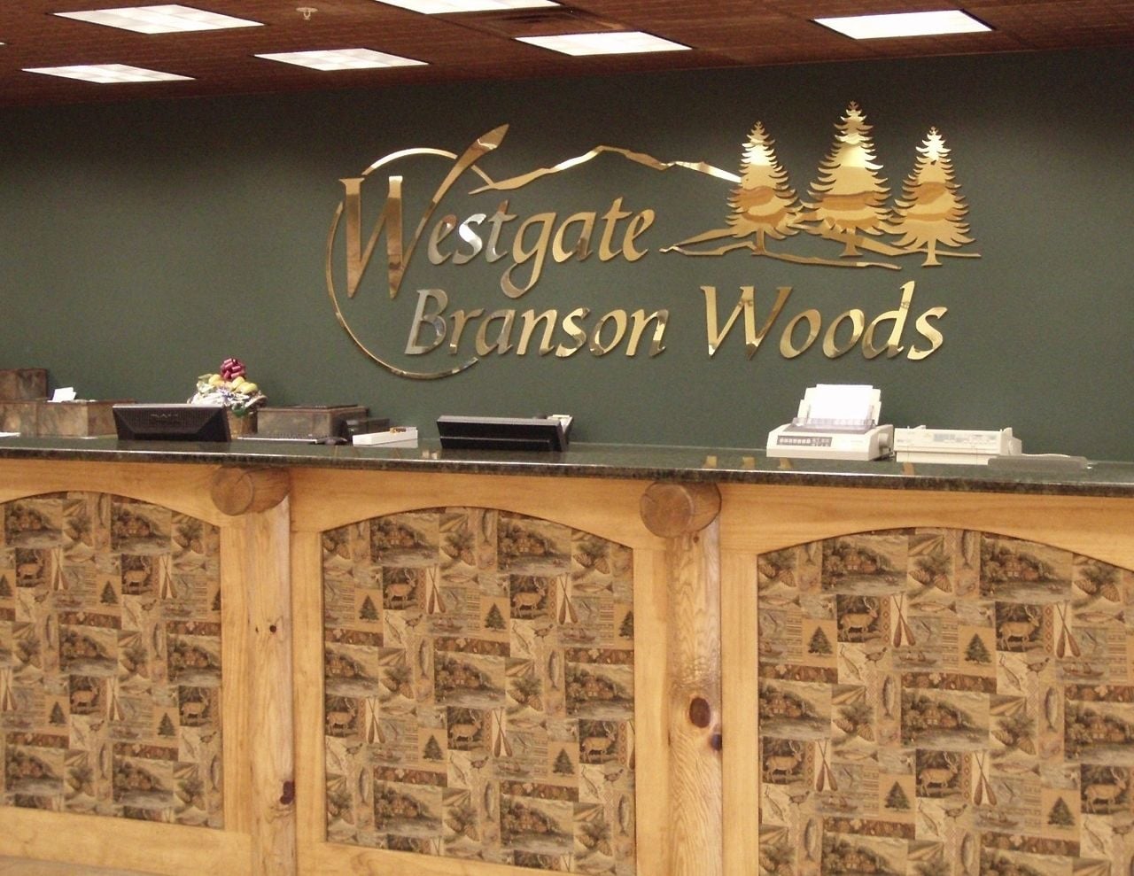Un comptoir d’accueil orné du logo de Westgate Branson Woods, avec un design en bois et des motifs représentant la faune locale.