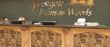Un comptoir d’accueil orné du logo de Westgate Branson Woods, avec un design en bois et des motifs représentant la faune locale.