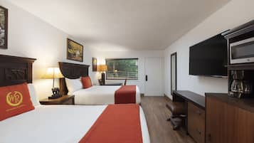 A hotel room with two beds, a TV, a coffee maker, and a desk.