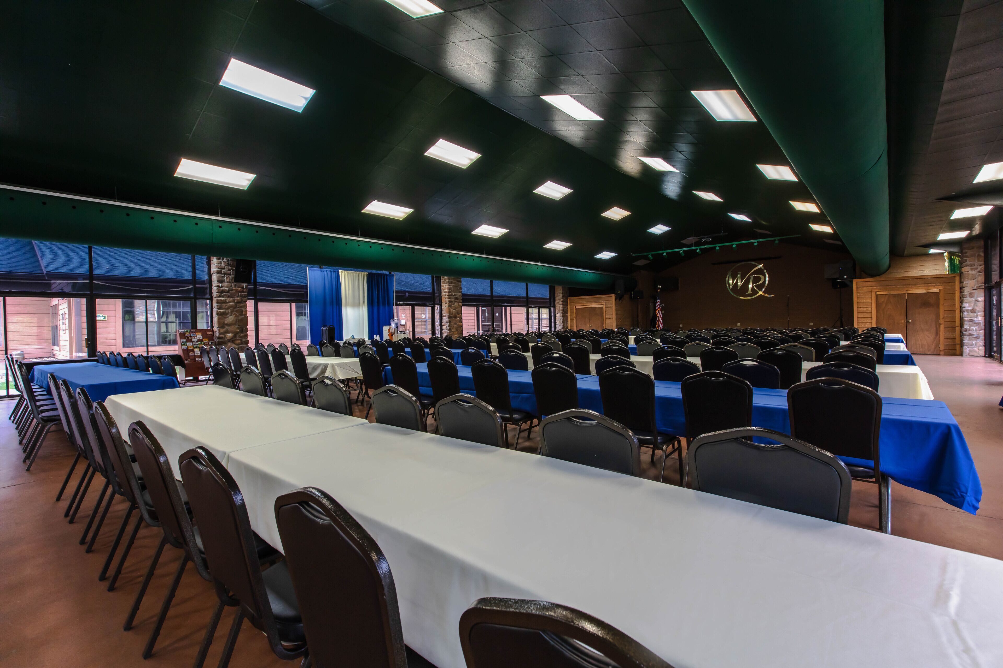 Une grande salle de conférence avec des rangées de tables et de chaises, un pilier en pierre et une vue sur l’ext érieur.