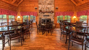 L’intérieur d’une cabane en rondins, avec une cheminée en pierre, une table à manger en bois et des chaises.