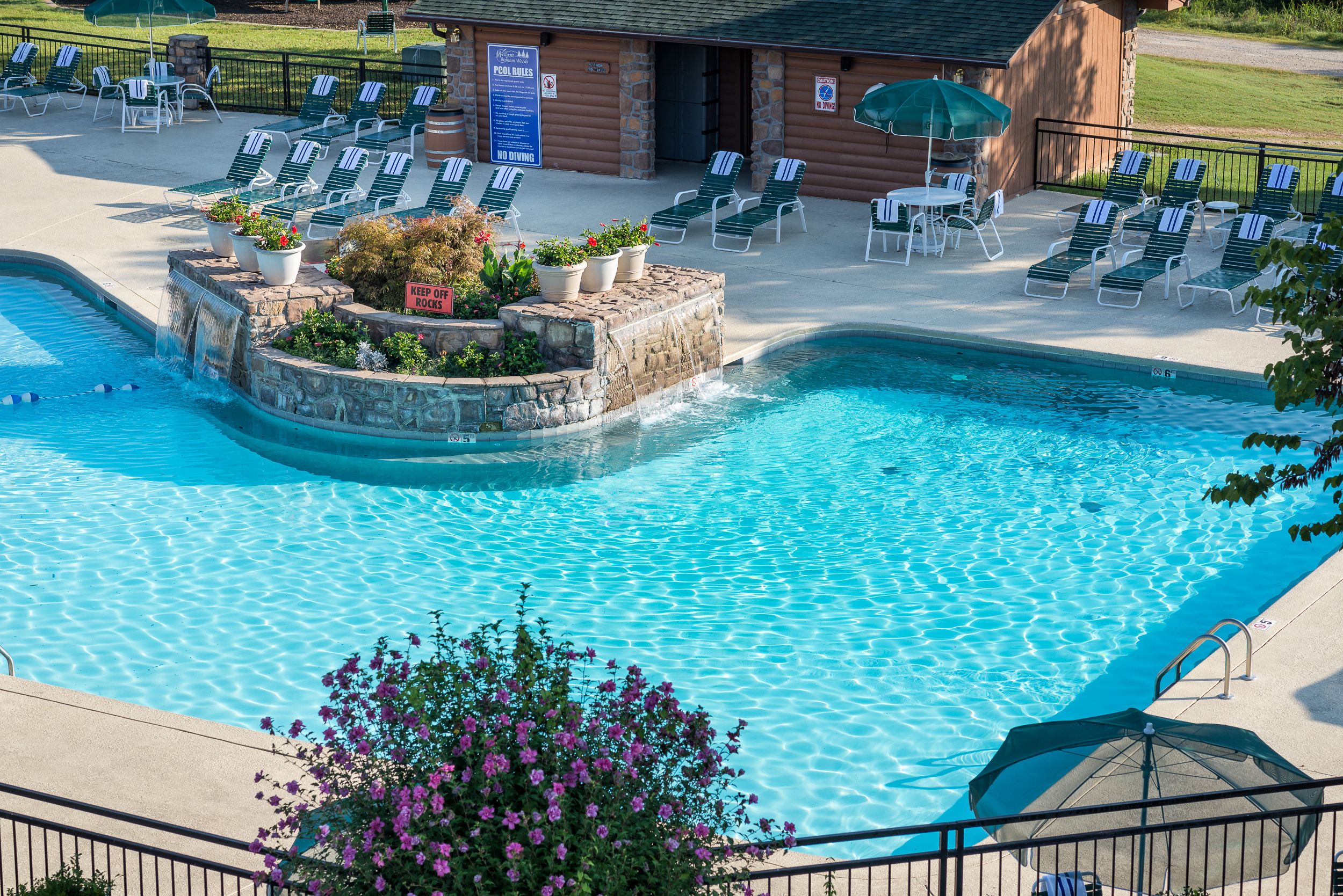 A pool area with lounge chairs, a waterfall feature, and a sign indicating 'No Diving'.