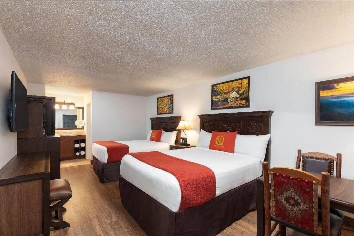 A hotel room with two beds, a desk, a chair, and artwork on the walls.