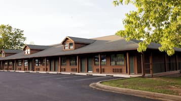 A row of log cabin-style buildings with a parking lot in front.