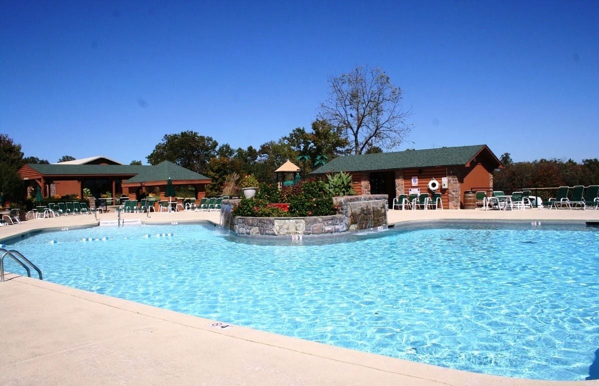 Una piscina con sillones de descanso y un pabellón.