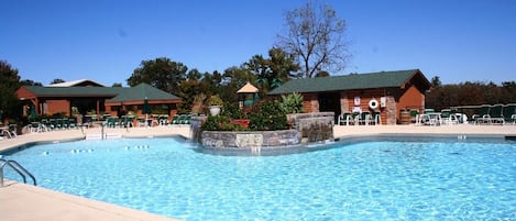 Una piscina con sillones de descanso y un pabellón.