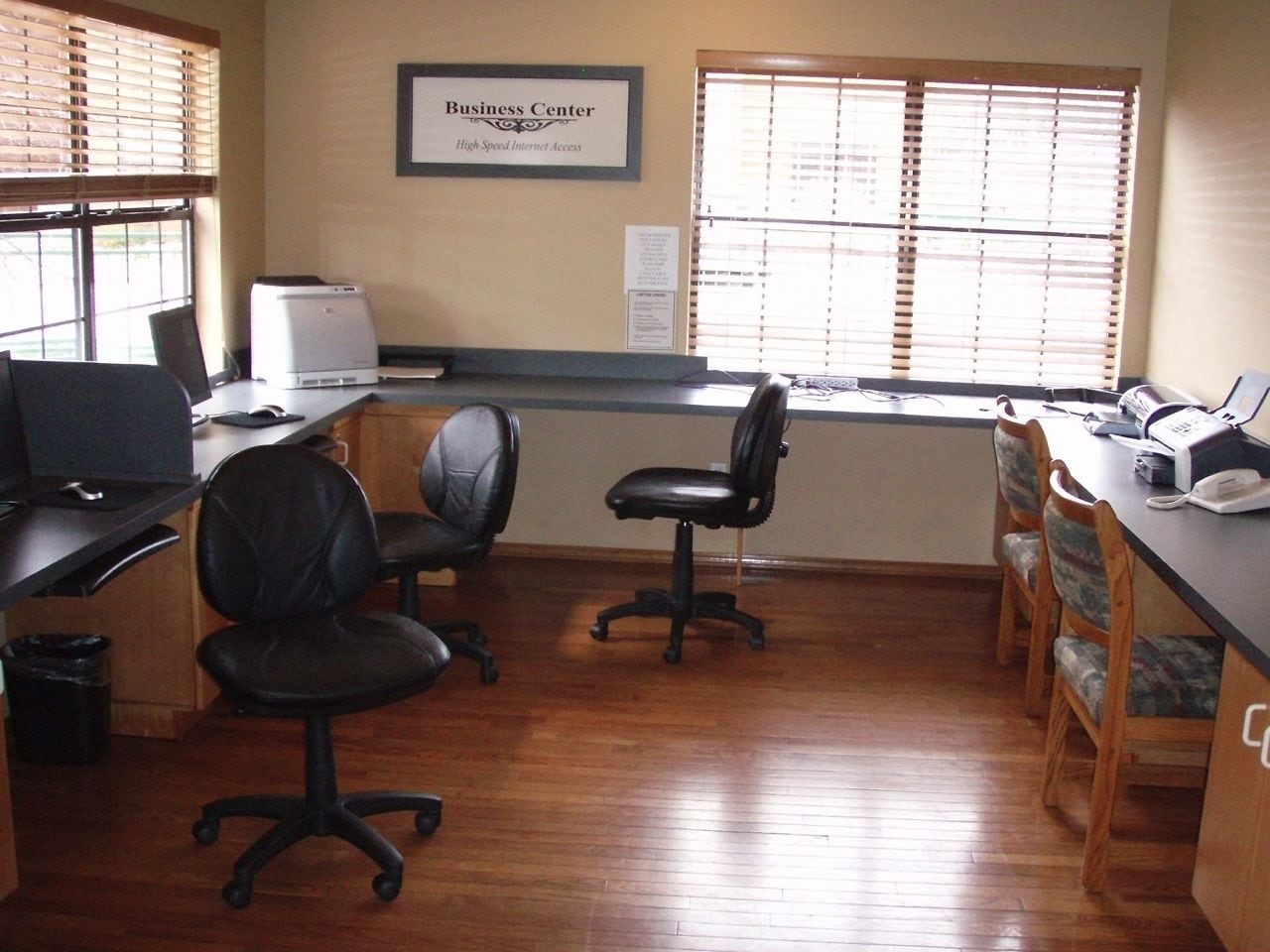 A business center with a computer, printer, and chairs.