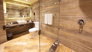 A modern bathroom with a glass-enclosed shower, marble walls, and a vanity with a sink and mirror.