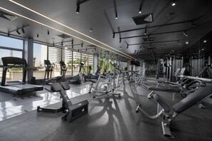 Un gimnasio con diverso equipo de ejercicio, amplias ventanas y diseño moderno.