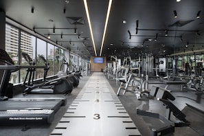 Un gimnasio con cintas de correr, máquinas de pesas y un amplio ventanal con espejos.