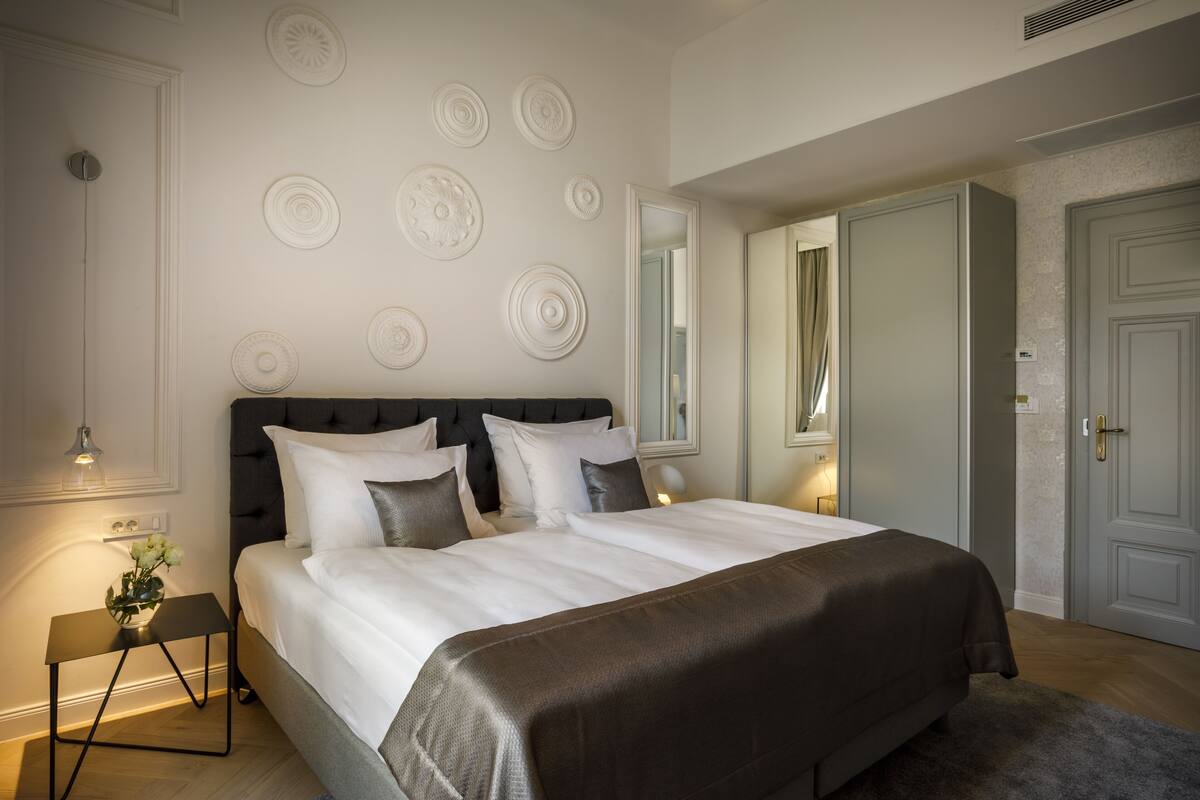 Une chambre avec un grand lit, une table de chevet avec une lampe et des éléments décoratifs fixés au mur.