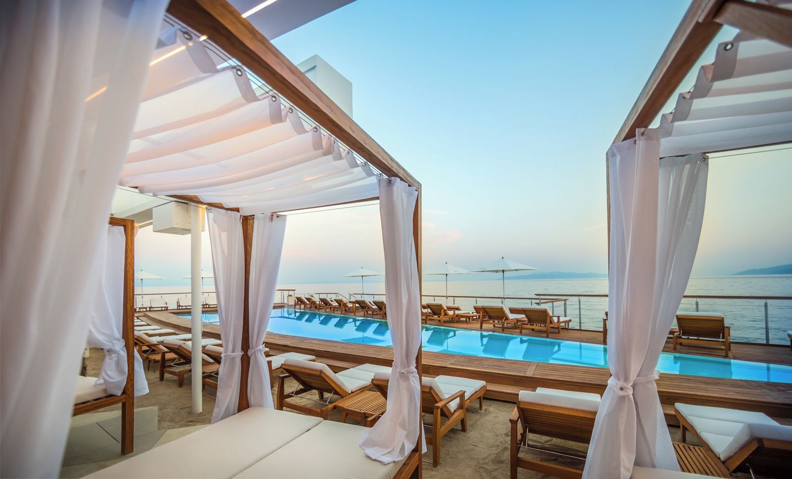 Zona junto a la piscina con tumbonas y vistas al mar.