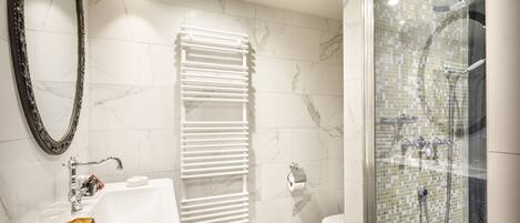 Un baño moderno con un lavabo blanco, un perchero, un inodoro y una zona de ducha.