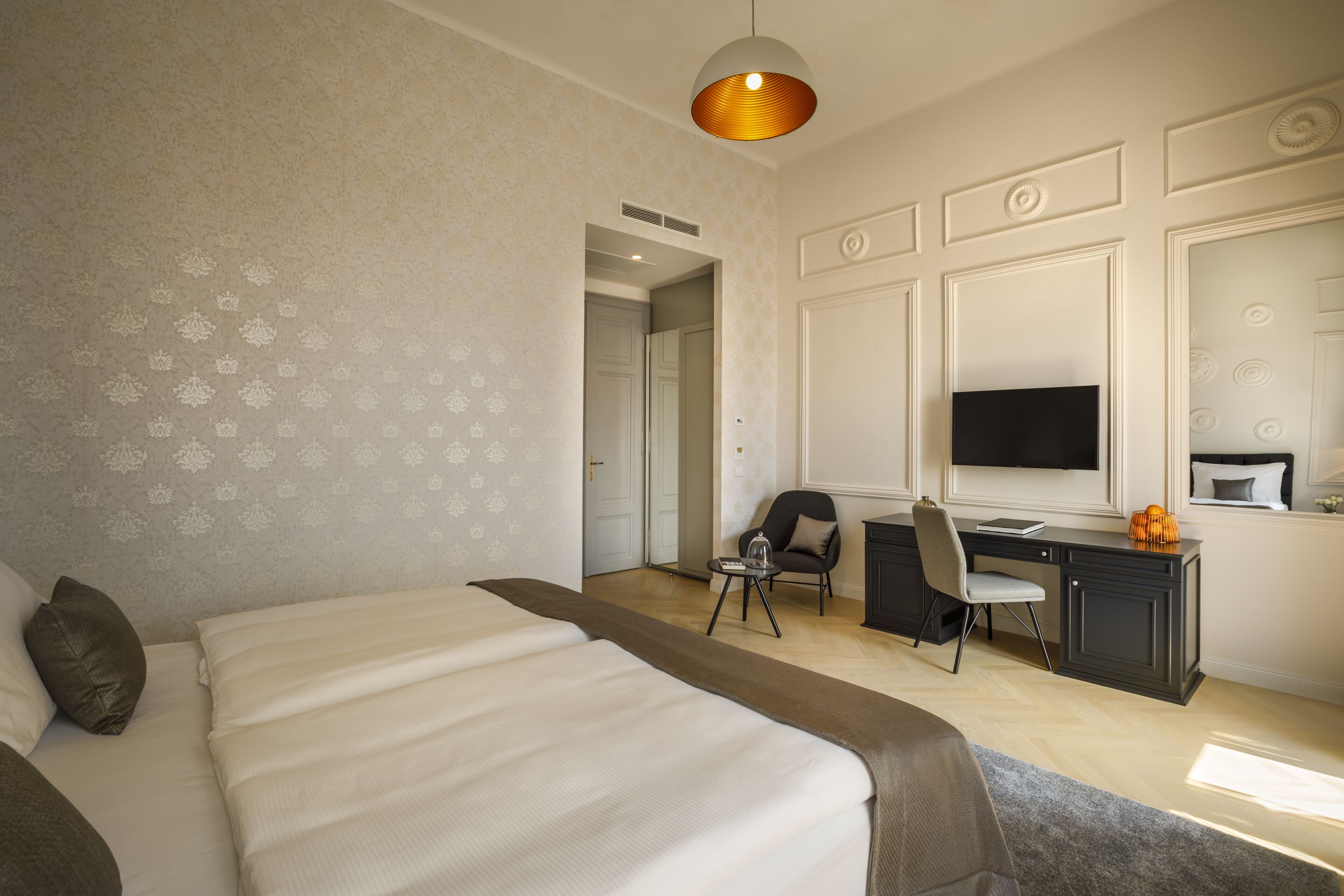 A hotel room with a large bed, a desk with a chair, a television, and a decorative pumpkin on the desk.