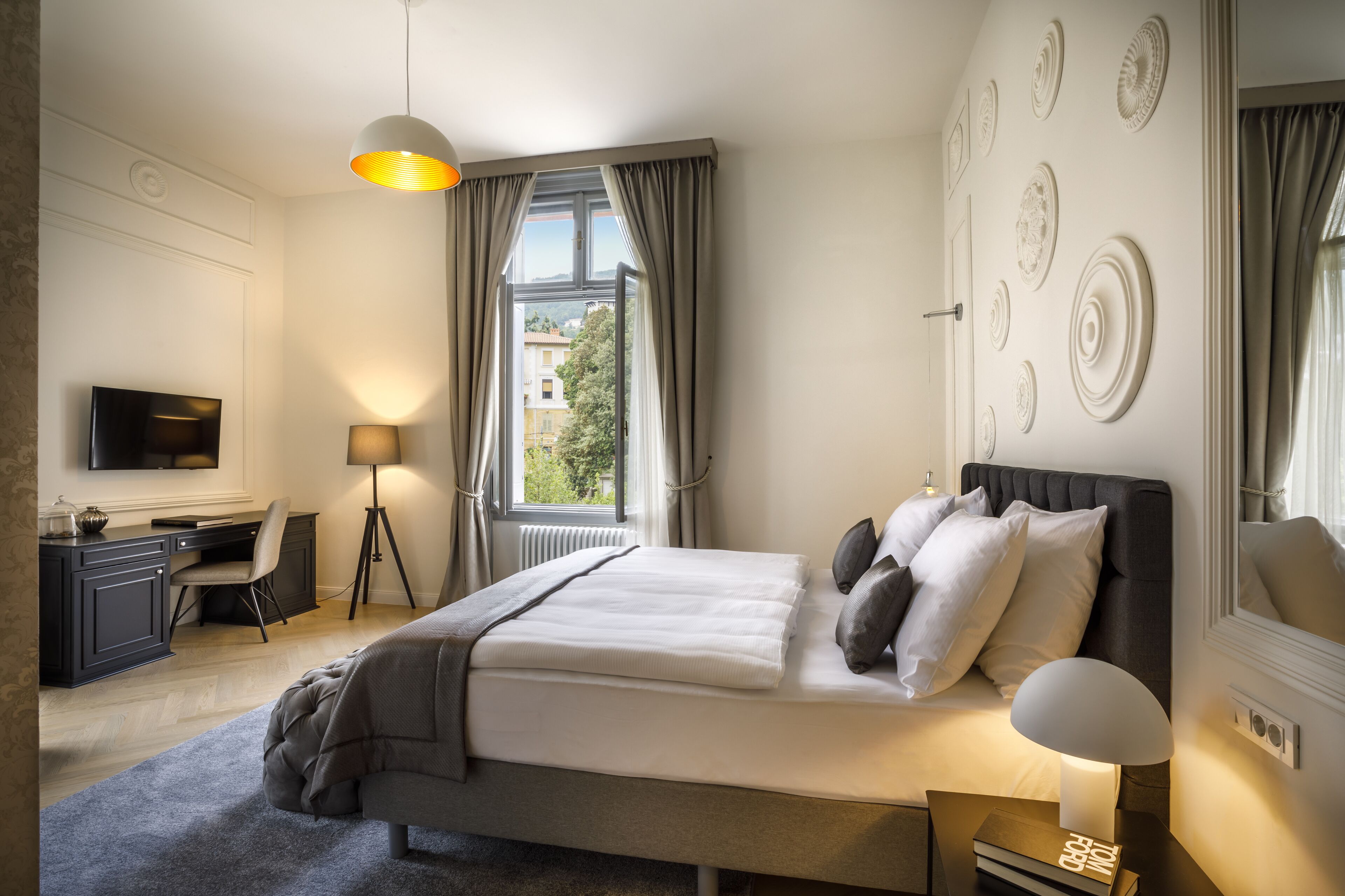 Un dormitorio ordenado con cama, mesita de noche, lámpara y un escritorio con silla.