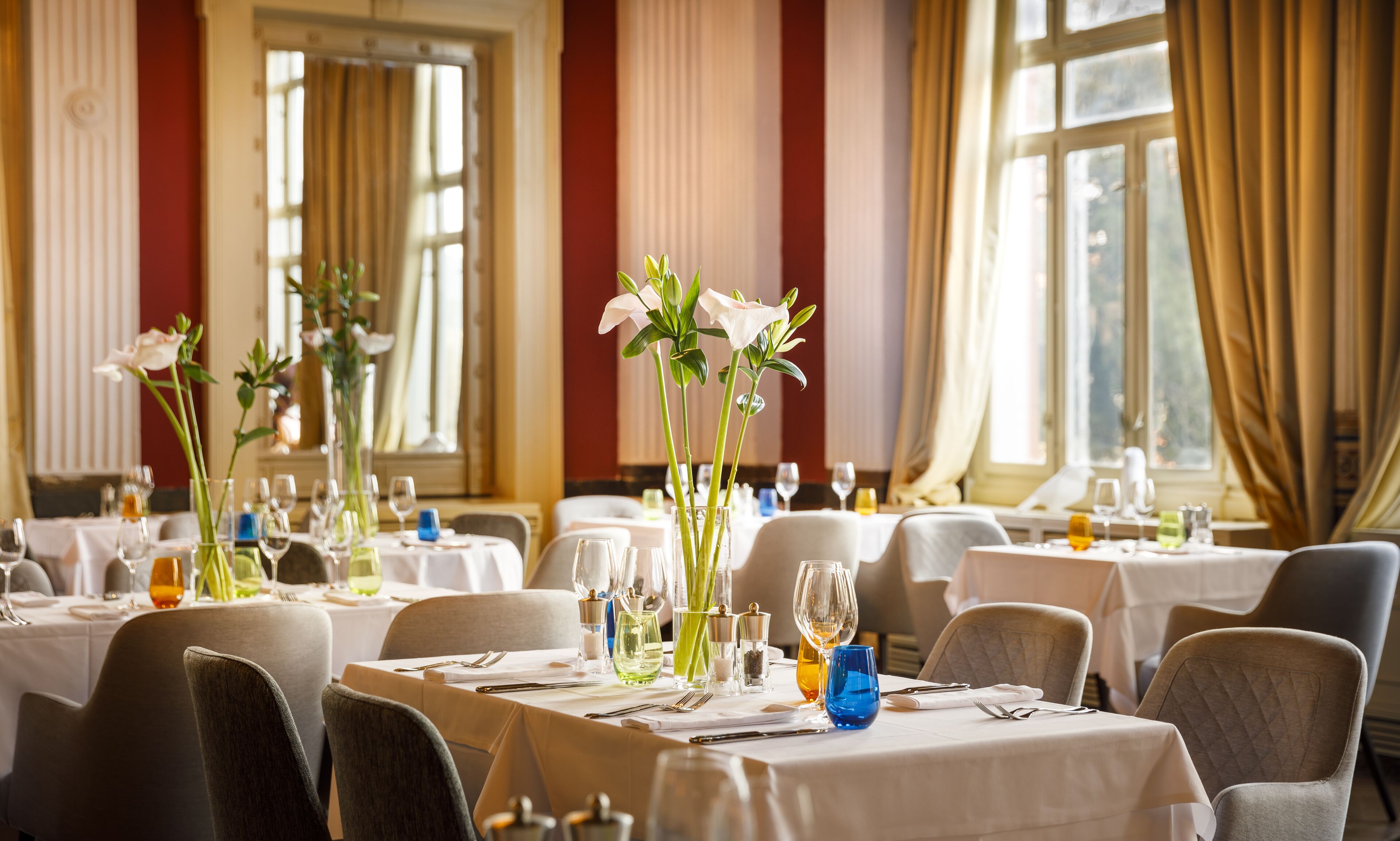 A dining area with tables set for a meal, featuring white tablecloths and glassware.