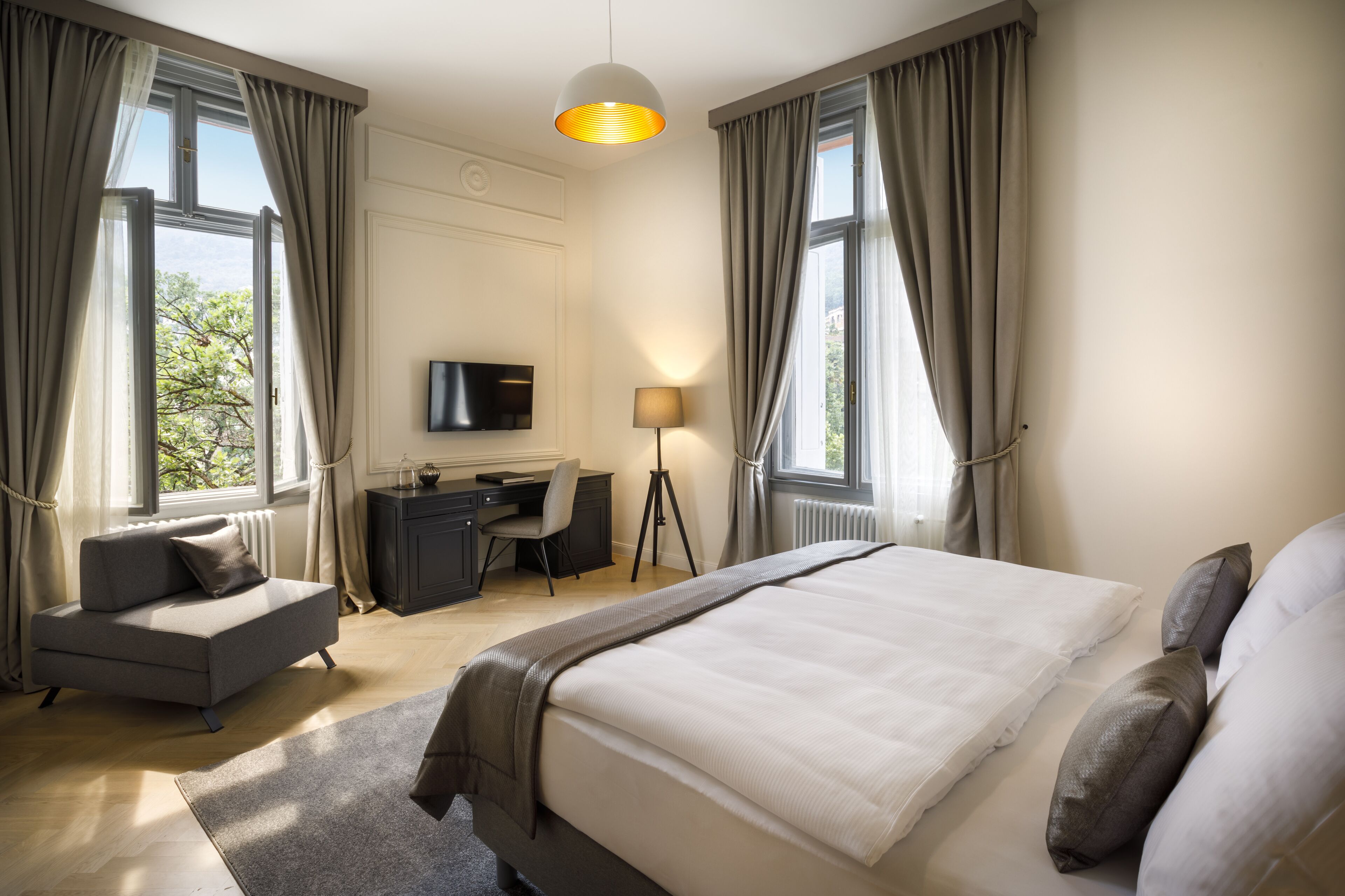 A modern hotel room with a large bed, a desk, and a TV.