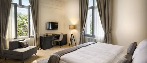 A modern hotel room with a large bed, a desk, and a TV.