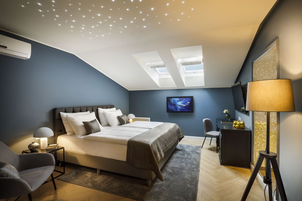 Une chambre moderne avec un grand lit, un bureau, une chaise et une lampe.