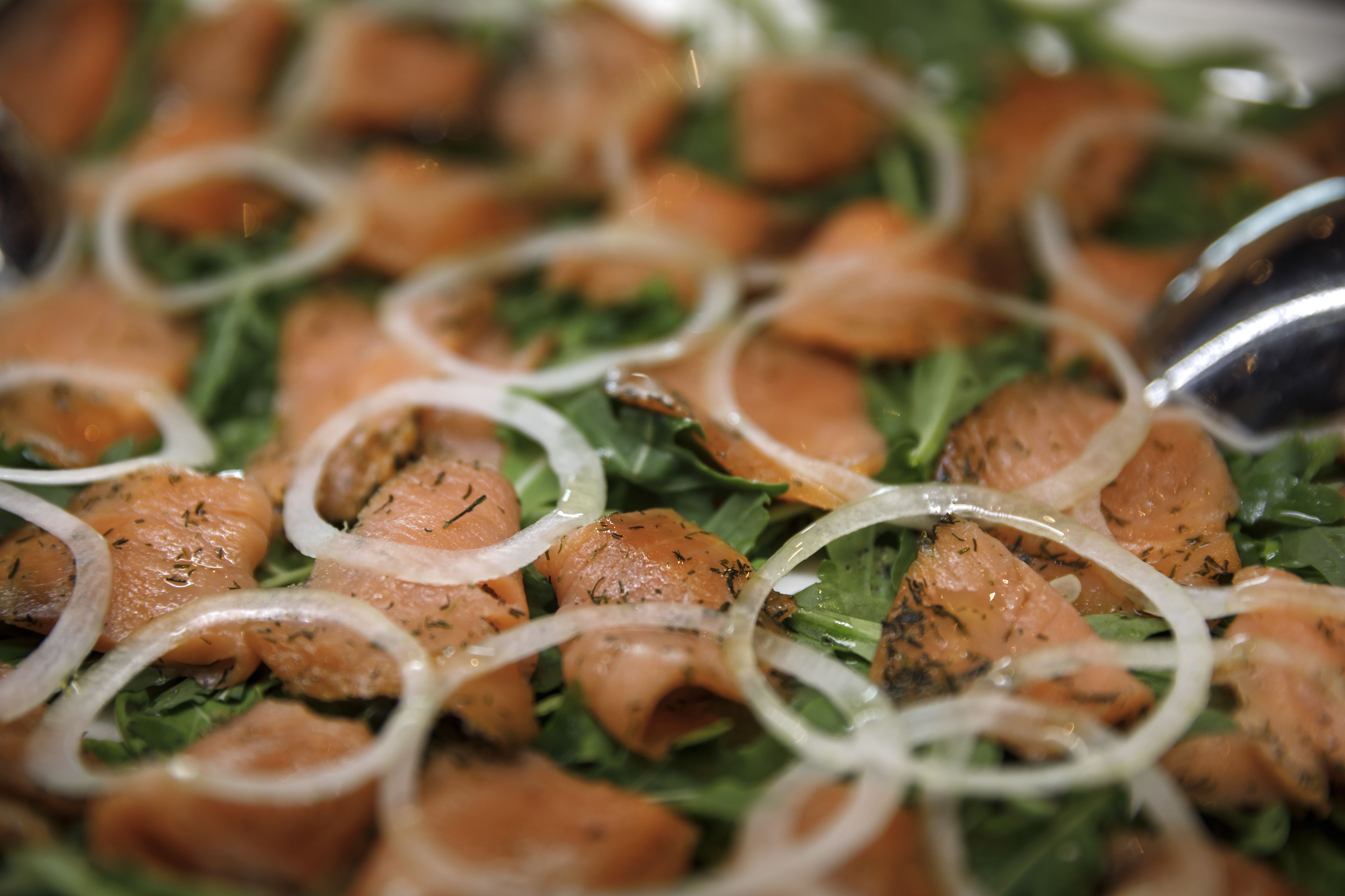 A close-up of a salad with salmon, onions, and greens.
