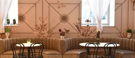 A modern interior with a curved sofa, round tables, and chairs. There are decorative wall panels and potted plants.