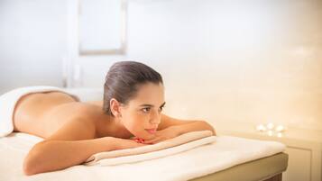 A person lying on a massage table in a spa setting.